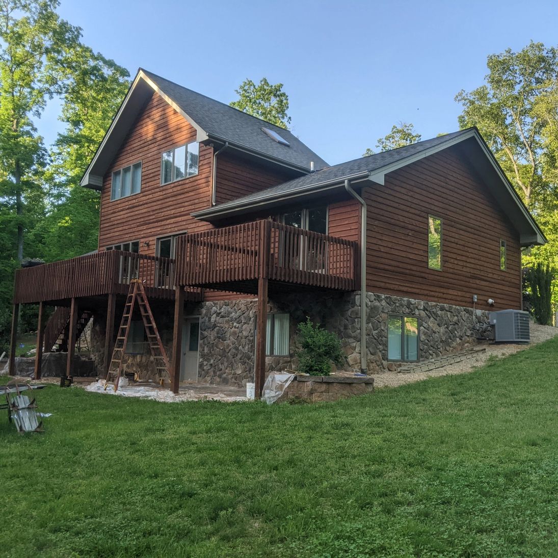 Freshly stained cedar-sided home with wraparound deck