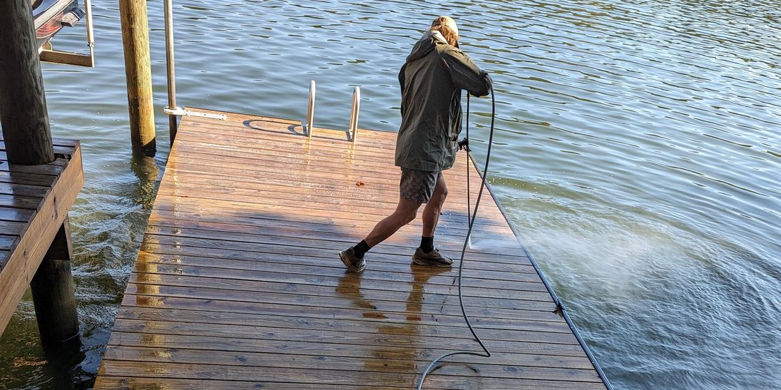 Robert Grice pressure washing a lakefront dock